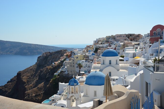 Whitewashed houses and blue domes along the caldera rim above the sea